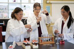 Teacher working with two students on science experiment at Mary MacKillop Catholic College Wakeley